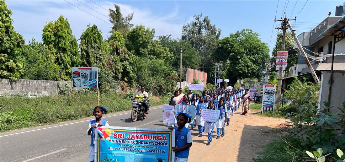 Students walking an awareness rally along the main road behind the school banner