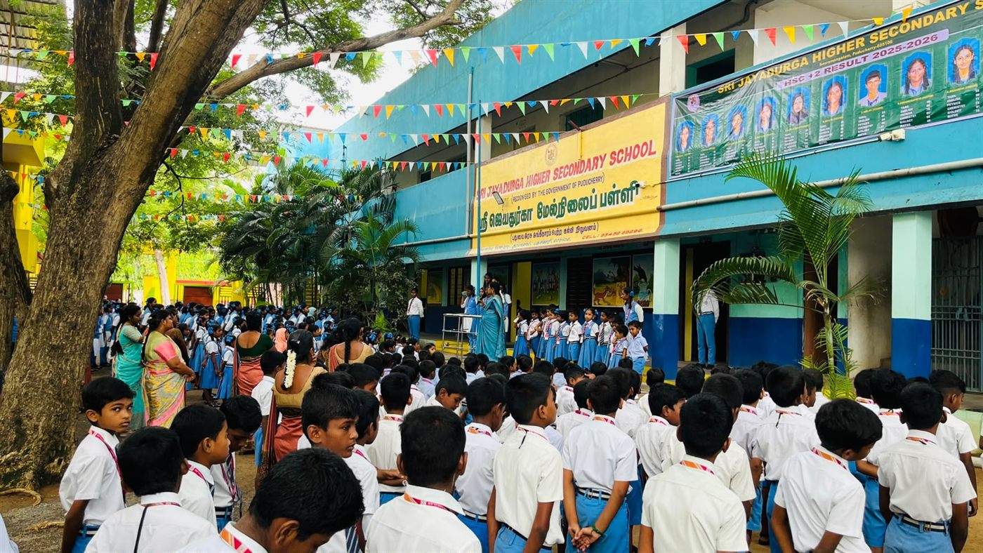 The front of Sri Jayadurga English Higher Secondary School, with students gathered under the trees