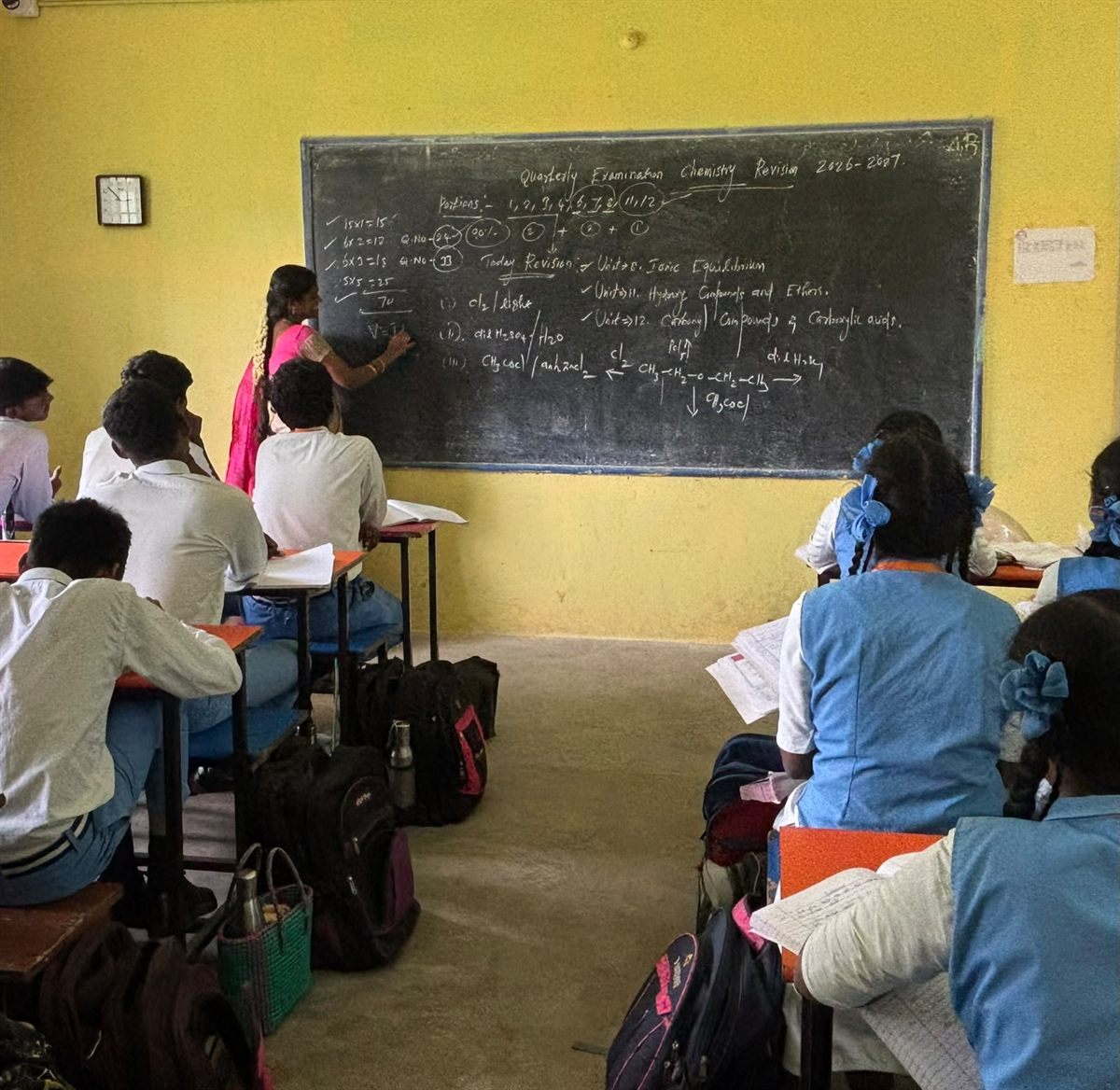 A middle school class, the teacher writing the day&rsquo;s lesson on the board