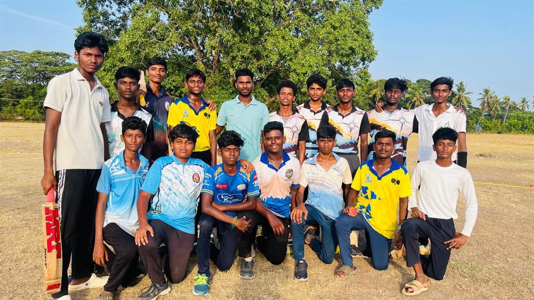 Boys of the team gathered on the ground, one of them with a bat